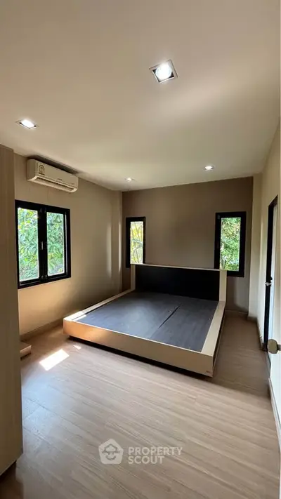 Spacious bedroom with modern design and large windows offering natural light and garden views.
