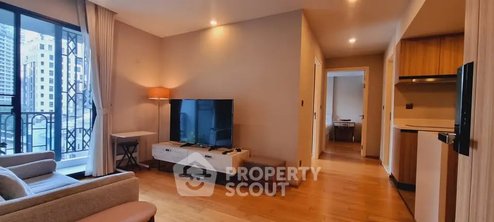 Modern living room with open layout, featuring a large TV, stylish furniture, and a view of the cityscape.