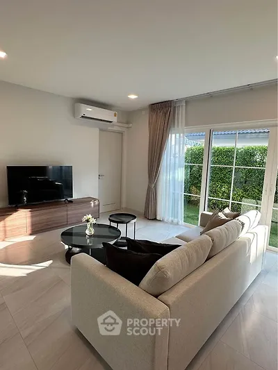 Modern living room with cozy sofa and large window overlooking garden