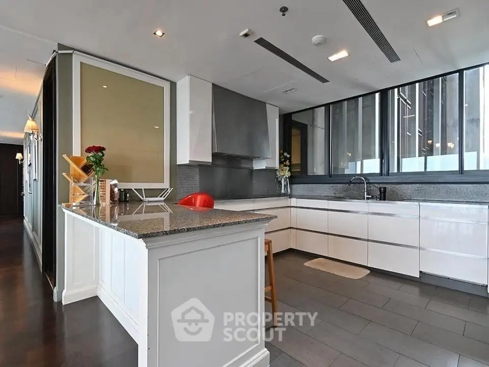 Modern kitchen with sleek white cabinetry and granite countertops in luxury apartment.