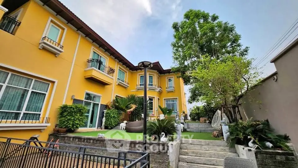 Charming yellow two-story house with lush garden and elegant outdoor decor