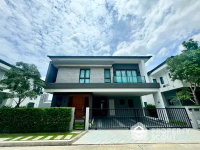 Modern two-story house with sleek design and lush greenery in a serene neighborhood.