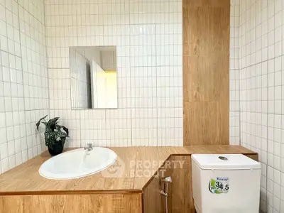 Modern bathroom with stylish wooden accents and sleek white tiles, featuring a built-in sink and toilet.