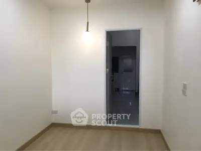 Minimalist room with light wood flooring and pendant light