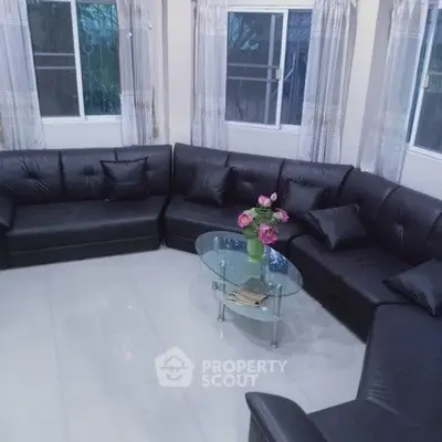 Spacious living room with modern black leather sectional sofa and glass coffee table, perfect for relaxation.