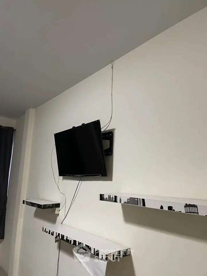 Modern living room with wall-mounted TV and stylish shelves.