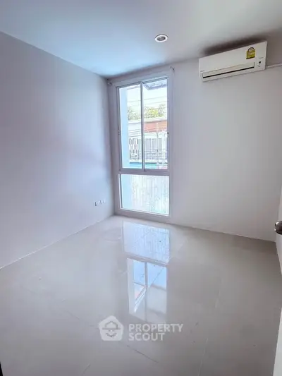 Bright empty room with large window and air conditioning, perfect for customization.