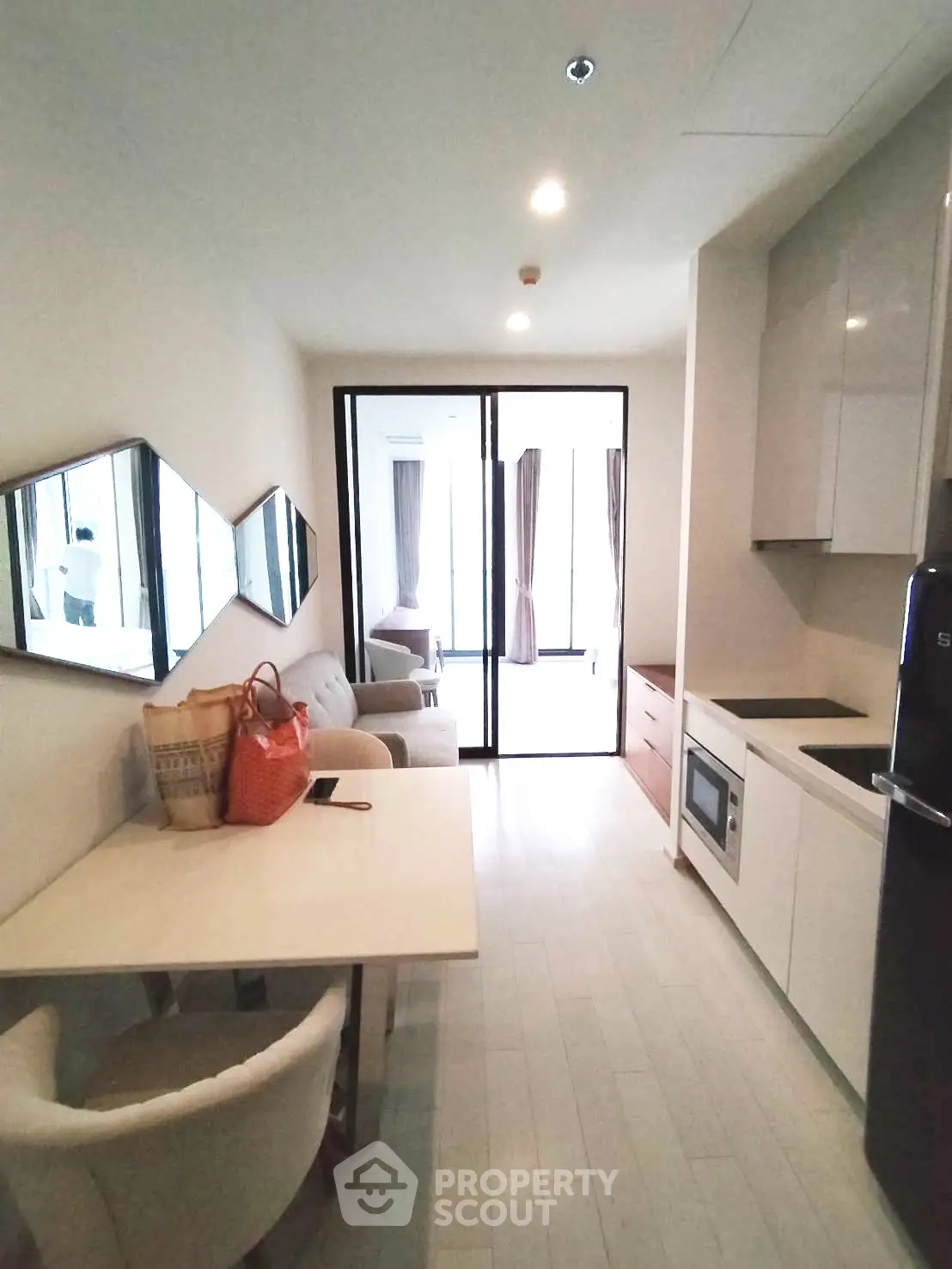 Modern apartment interior with open kitchen and cozy living area, featuring sleek design and natural light.