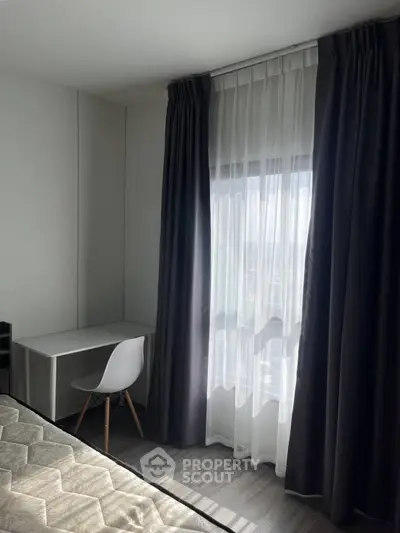Modern bedroom with sleek desk and chair by a sunlit window, featuring elegant curtains and a comfortable mattress.