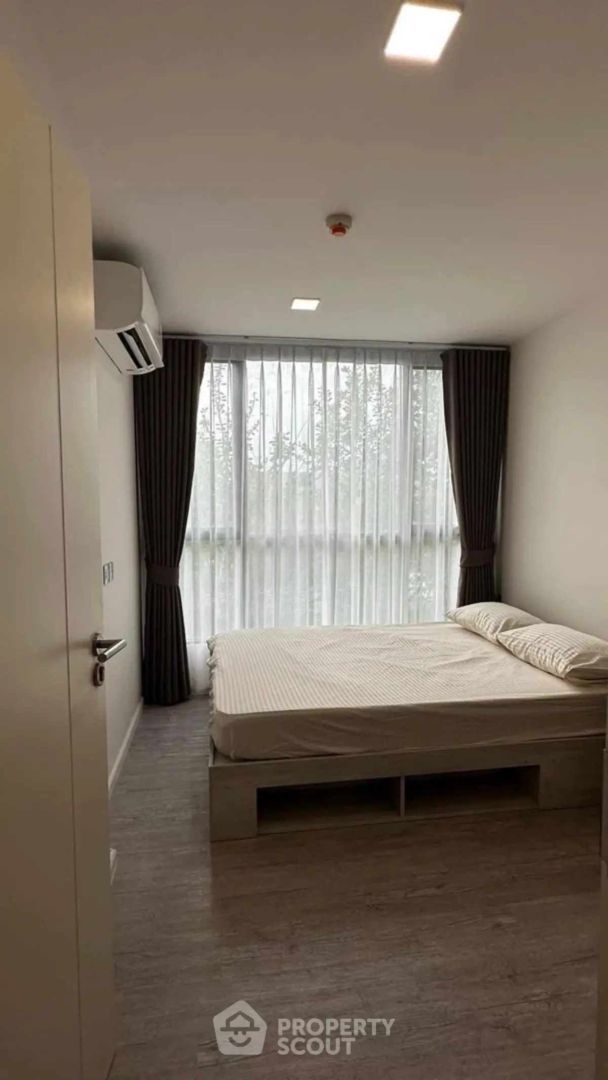 Cozy bedroom with large window and modern decor in a stylish apartment.