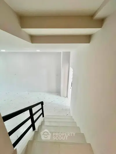 Modern staircase leading to a bright, open living space with sleek design.