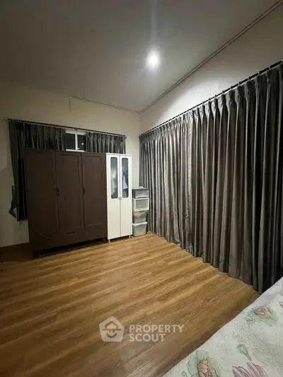 Spacious bedroom with wooden flooring and ample natural light