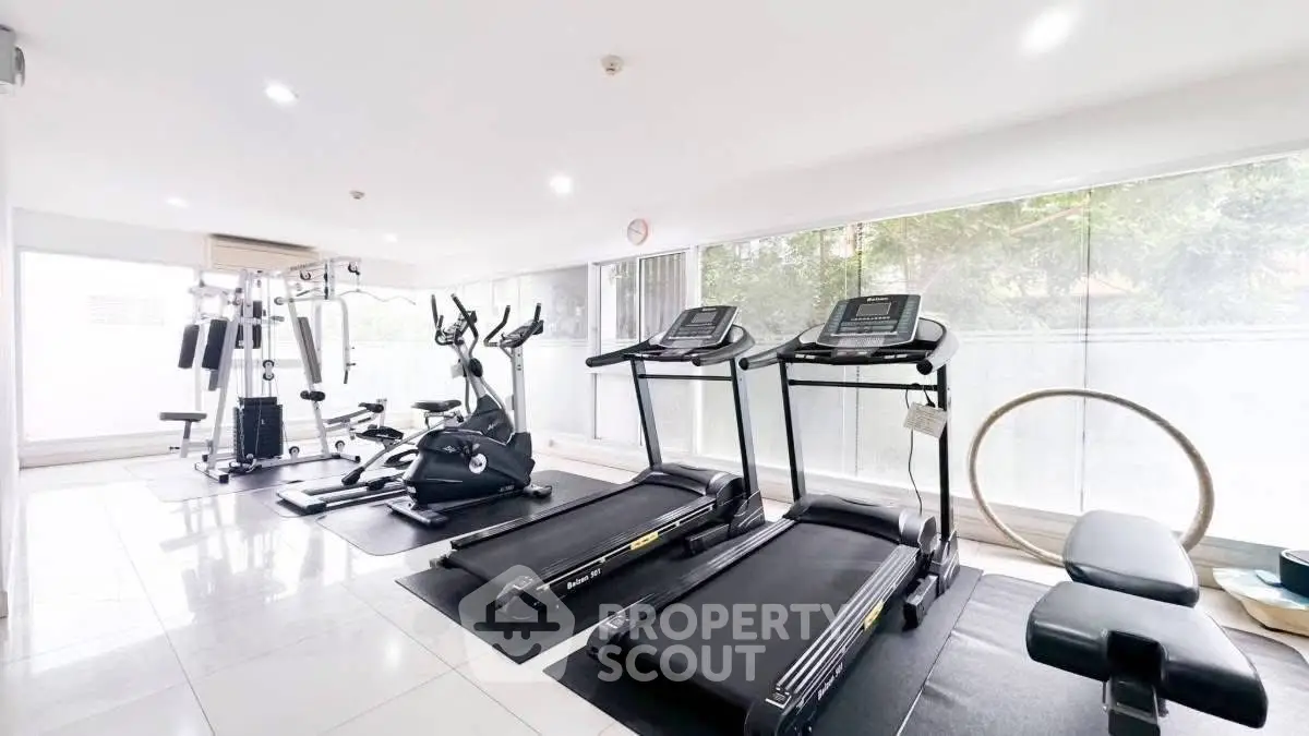 Spacious modern gym with state-of-the-art equipment and large windows for natural light.