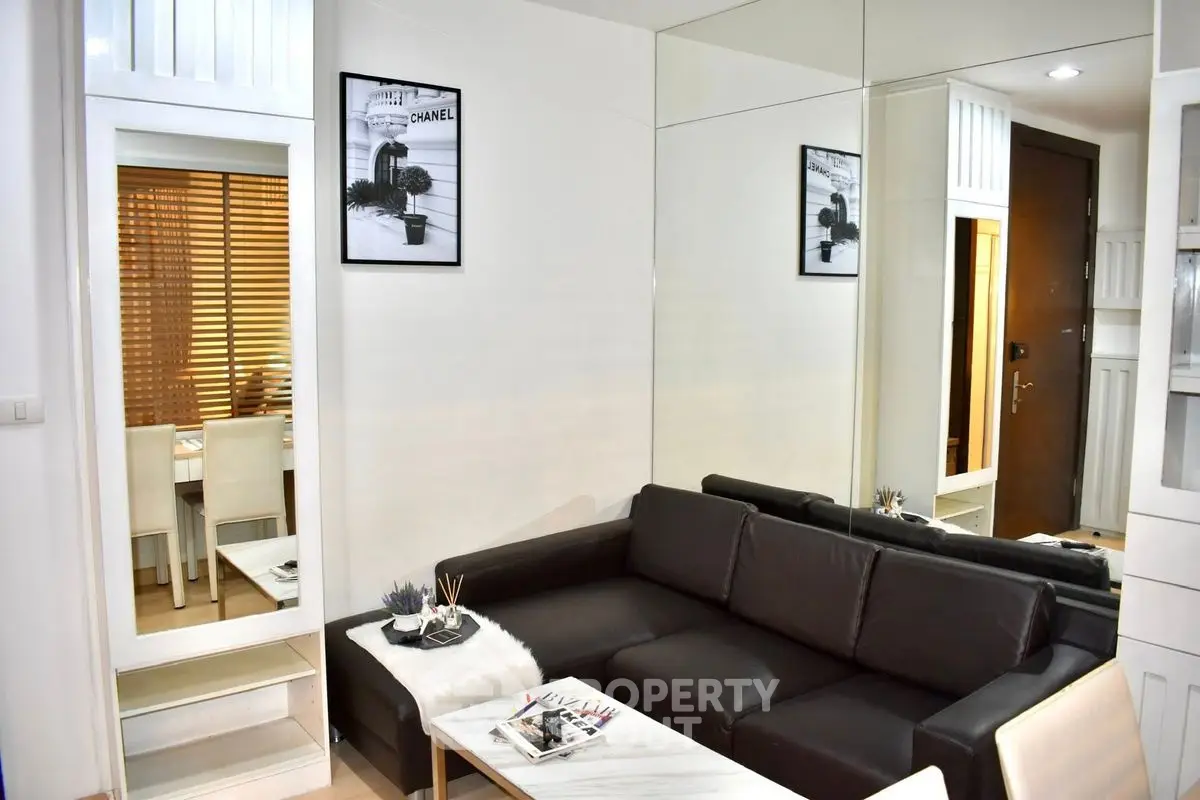 Modern living room with sleek black sofa and stylish decor in a chic apartment.