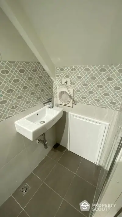 Compact bathroom with modern sink and geometric tile design