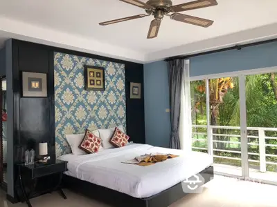 Luxurious bedroom with elegant decor and garden view, featuring a stylish ceiling fan and large windows.