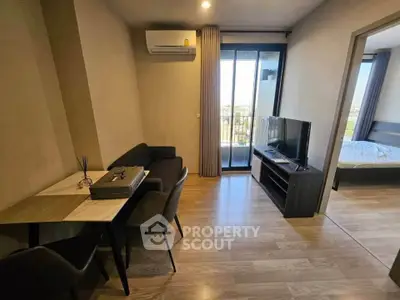 Modern apartment interior with living room and bedroom, featuring sleek furniture and a balcony view.