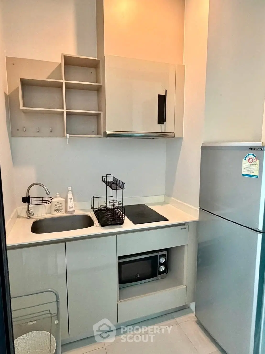 Modern compact kitchen with sleek cabinetry and built-in appliances in a stylish apartment.