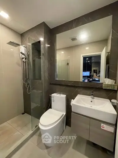 Modern bathroom with glass shower and sleek fixtures in contemporary apartment.