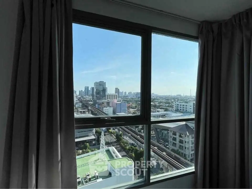 Stunning cityscape view from a high-rise window with clear blue sky.