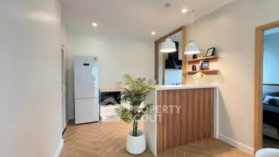 Modern kitchen with sleek design, featuring a white fridge and stylish lighting.
