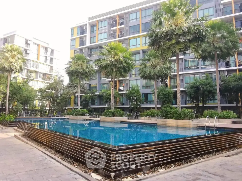 Modern apartment complex with a stunning outdoor pool and lush palm trees.