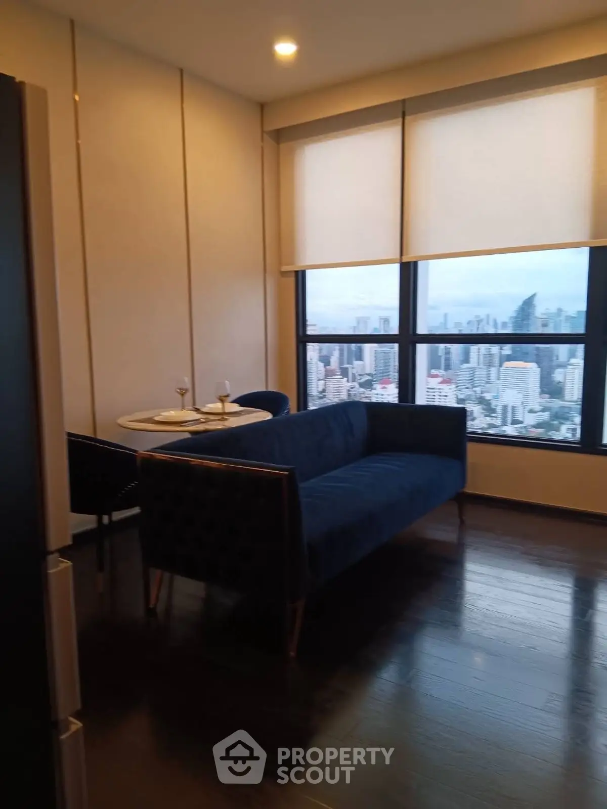 Modern living room with stunning city view, featuring elegant furniture and large windows.