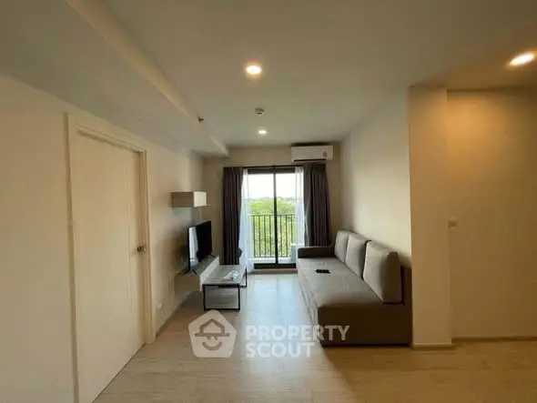 Modern living room with large window and minimalist decor, featuring a comfortable sofa and wall-mounted TV.