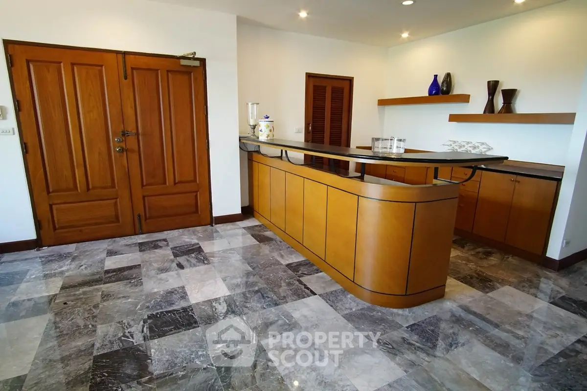 Spacious home bar area with elegant wooden cabinetry and marble flooring