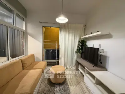 Cozy living room with modern decor and balcony access, featuring a plush sofa and sleek TV setup.