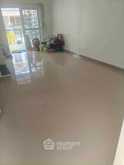 Spacious empty room with glossy tiled floor and large window for natural light.