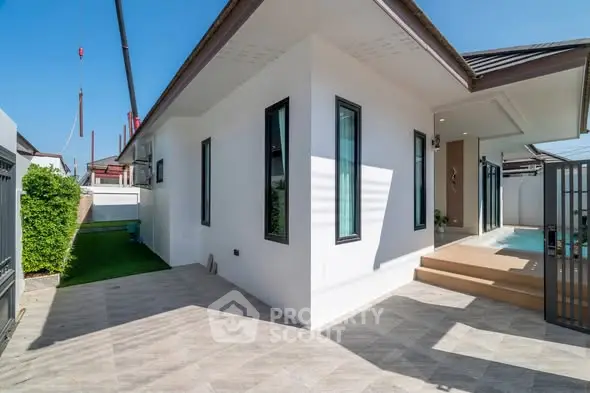Modern single-story house with clean lines, large windows, and a small pool in a sunny backyard.