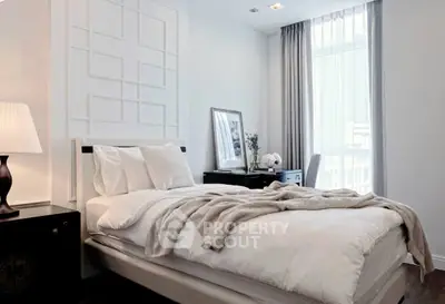 Elegant bedroom with modern decor, featuring a cozy bed, stylish lamp, and natural light from large window.