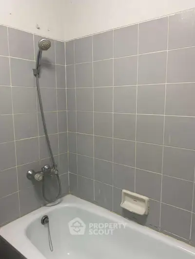 Simple bathroom with tiled walls and a bathtub featuring a handheld showerhead.