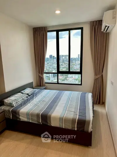 Modern bedroom with city view, featuring large window and stylish decor.