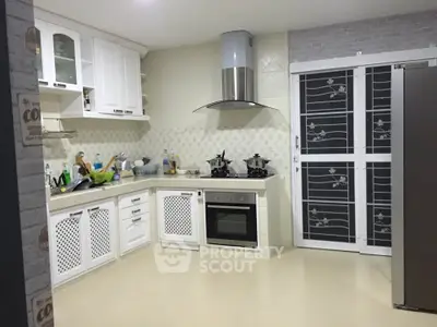 Modern kitchen with white cabinetry and built-in oven in stylish home.