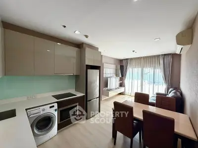 Modern open-layout kitchen and living room with sleek appliances and natural light.