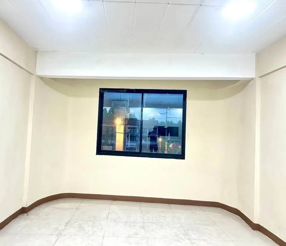 Spacious empty room with large window and bright lighting, ideal for customization.