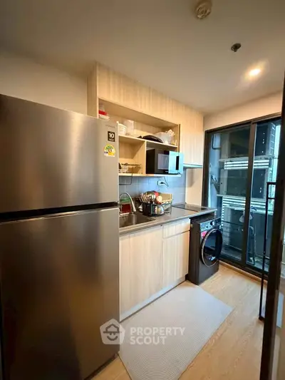 Modern kitchen with stainless steel fridge, washing machine, and balcony view.