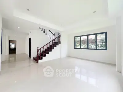 Spacious modern living room with elegant staircase and large windows
