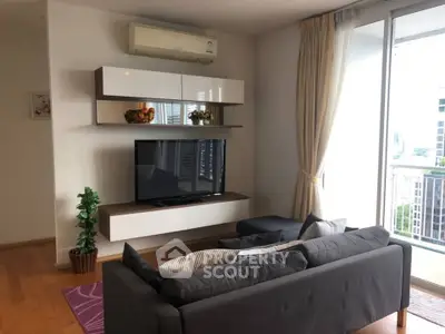 Modern living room with sleek furniture and large window offering city view.