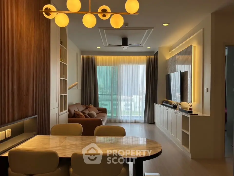 Modern living room with elegant lighting and stylish furniture, featuring a large window with city view.