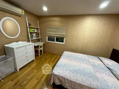 Cozy bedroom with wooden flooring, stylish decor, and ample natural light.