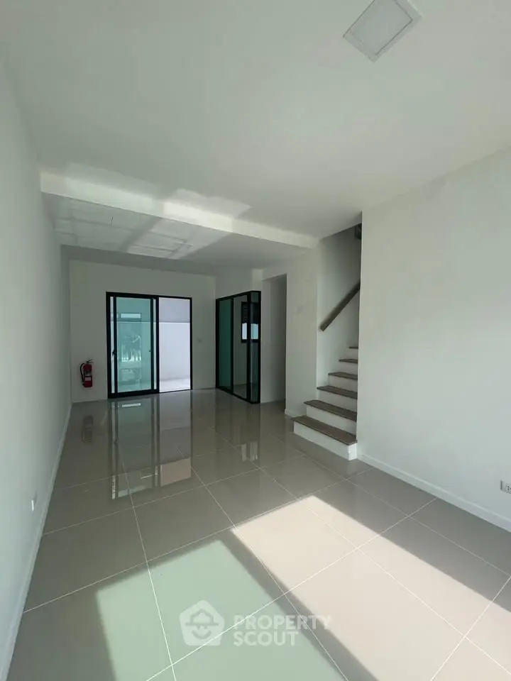 Spacious modern interior with sleek tile flooring and stairway, ideal for contemporary living.