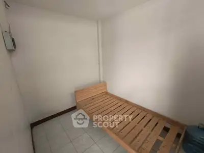Minimalist room with wooden bed frame and tiled floor, ideal for compact living spaces.