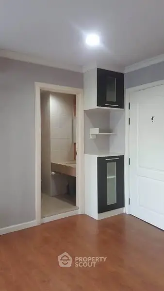 Modern apartment interior with sleek flooring and built-in storage near bathroom entrance.