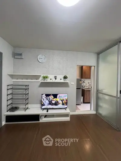 Modern living room with sleek TV stand and open kitchen view, perfect for urban living.