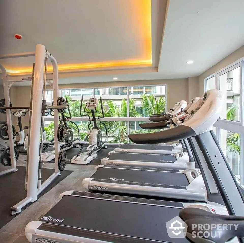 Modern gym with state-of-the-art equipment and large windows offering a garden view.