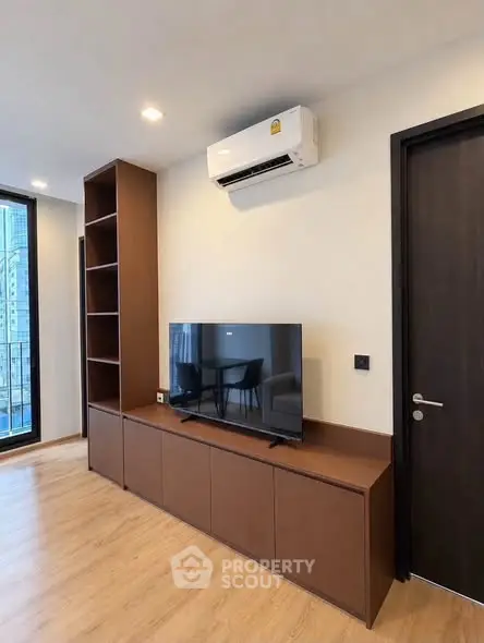 Modern living room with sleek TV unit and air conditioning, featuring wooden flooring and minimalist design.