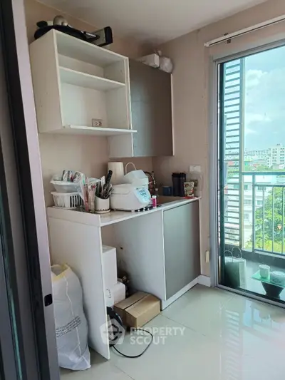 Compact kitchen with balcony view, featuring modern cabinets and appliances, ideal for urban living.
